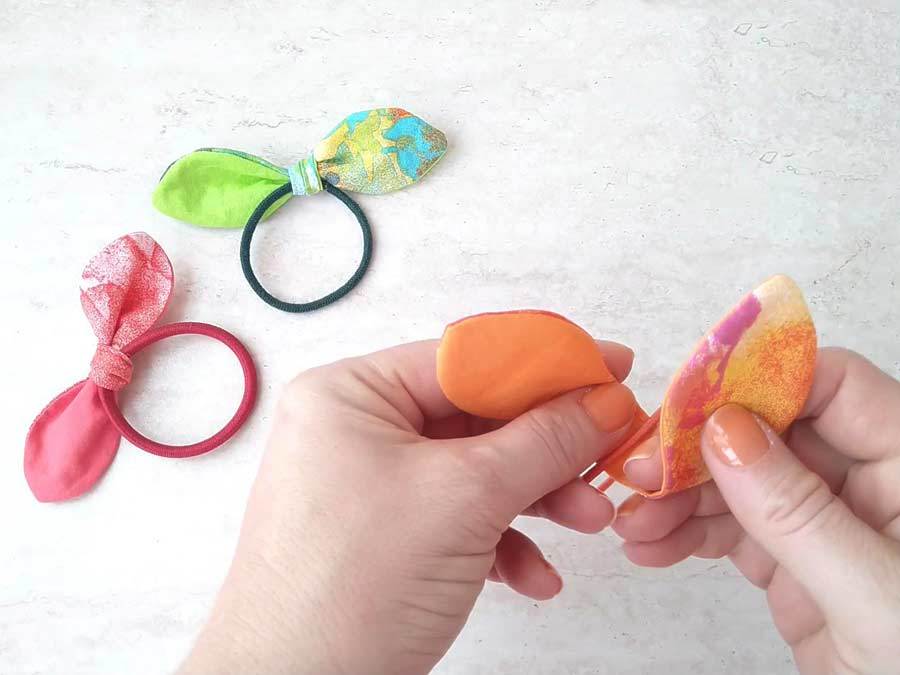 Tying the bunny ears knot bow around colorful rubber hair tie