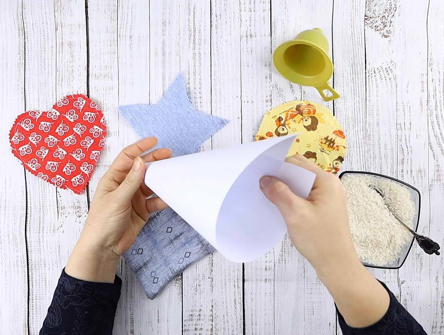 using a paper funnel to fill up a diy hand warmer with rice