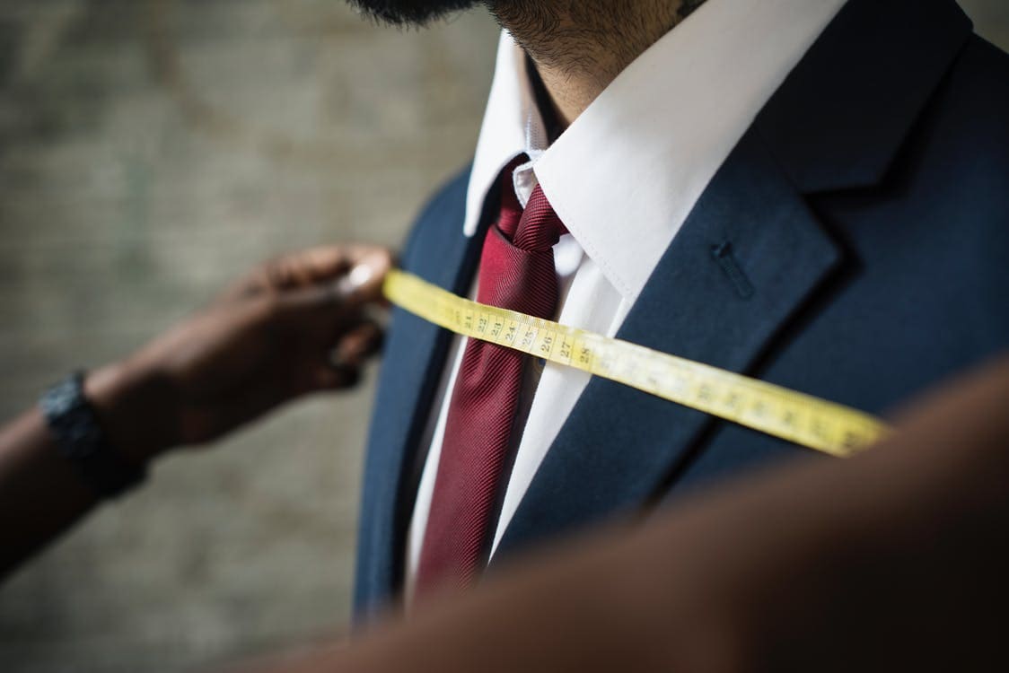 Tailor taking measurements of a client